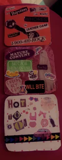 three cardboard decoupaged coasters. The first reads: Oh boy! I'm thirsting. Call kinky whores in leather gear. Get your sex magick on. 1-900-410-ROCK. The second features lisa frank stickers and an image of a ghost and reads: Mature content. Not for human use. Creeps get cut. Will bite. The third reads: Hot to go!