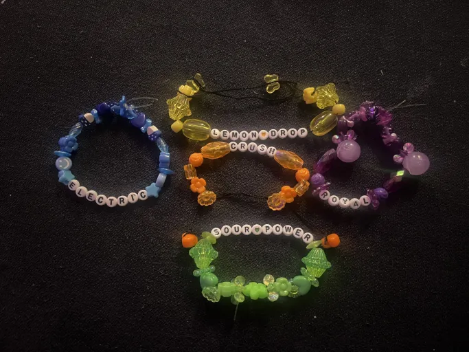 Colorful beaded bracelets with oddly shaped beads. One is yellow and reads 'lemon drop'. One is orange and reads 'crush'. One is green and reads 'sour power'. One is blue and reads 'electric'. One is purple and reads 'royal'.