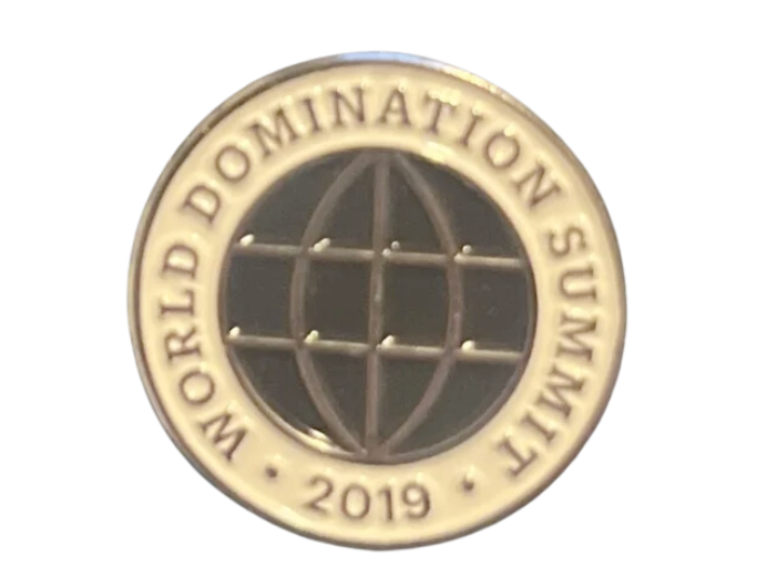 a pin with a black globe on it that reads 'World domination summit, 2019'.