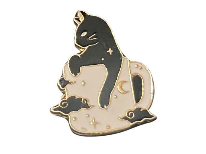 an enamel pin of a black cat in a coffee mug.